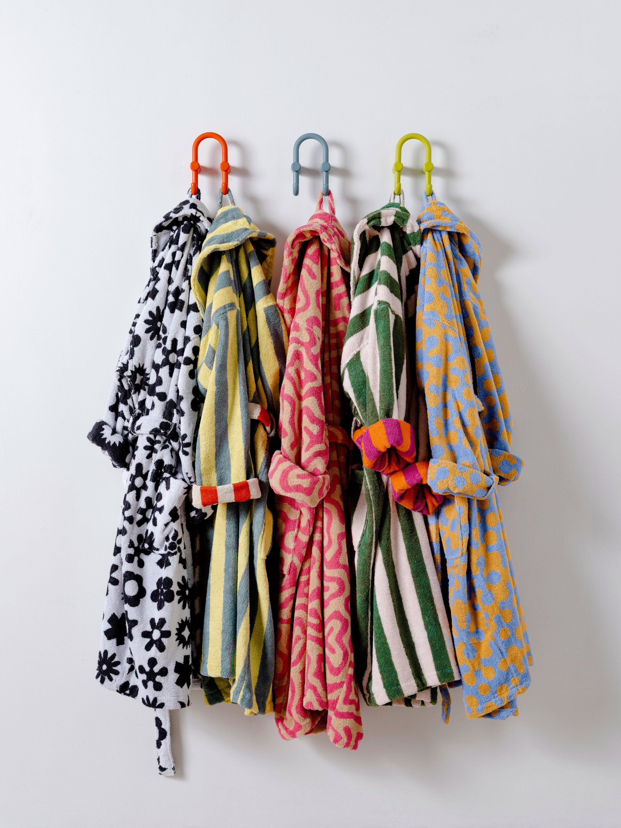 Two Dusen Dusen stripes bathrobes and three Dusen Dusen pattern bathrobes hang from hooks together