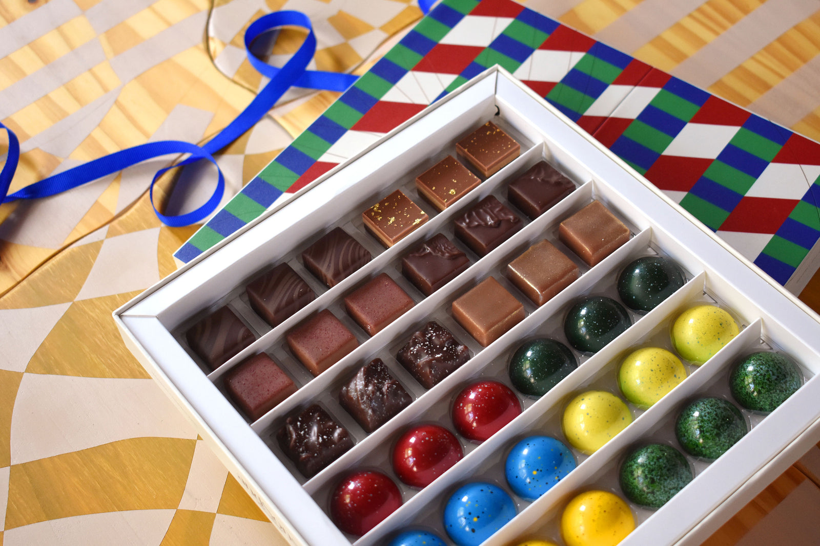 chocolates in box on table with ribbon