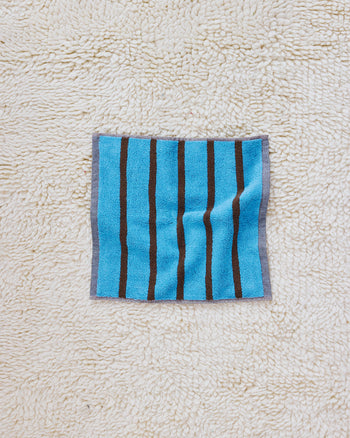 Blue and brown stripe washcloth on rug