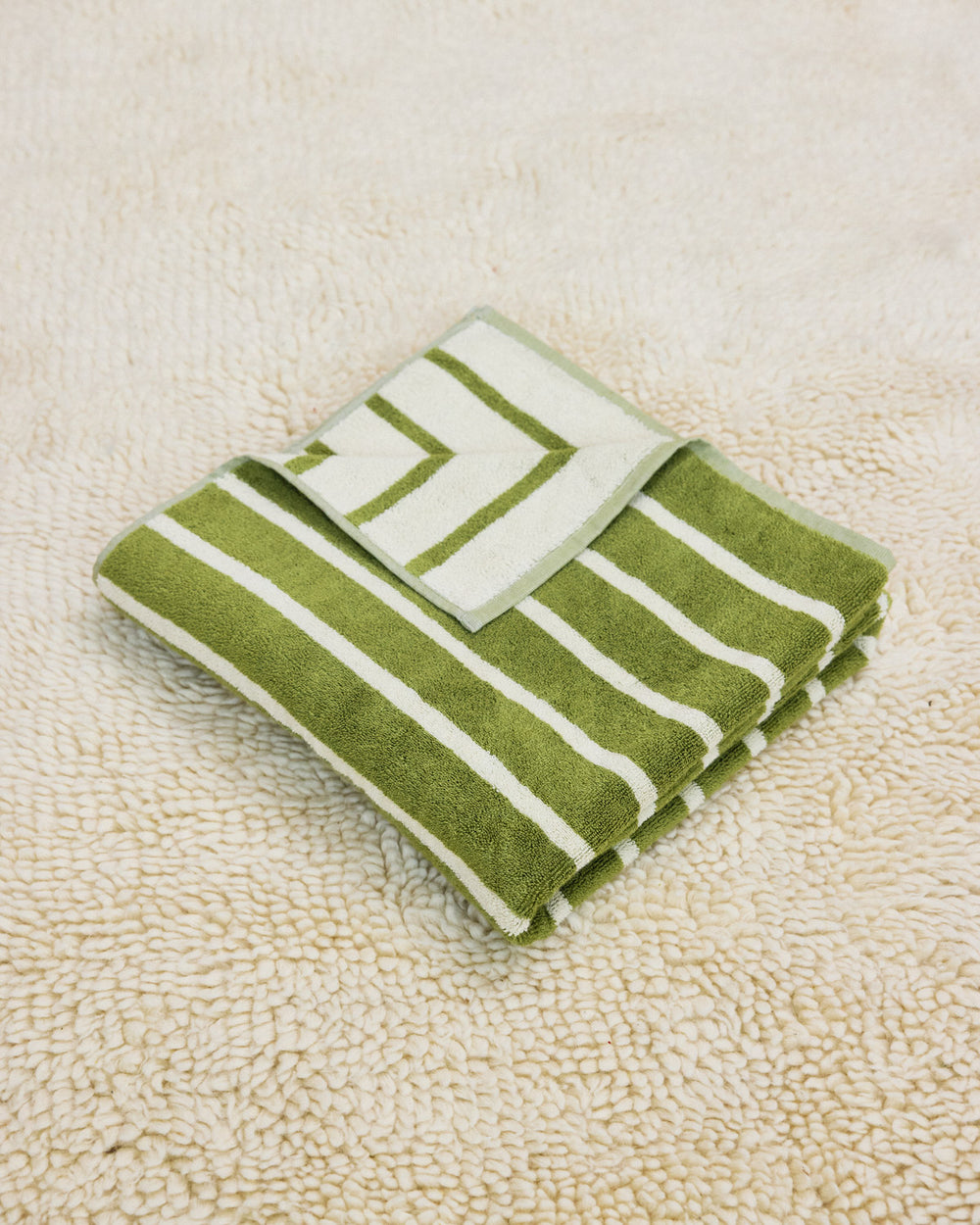 Green and white striped towel folded on a rug