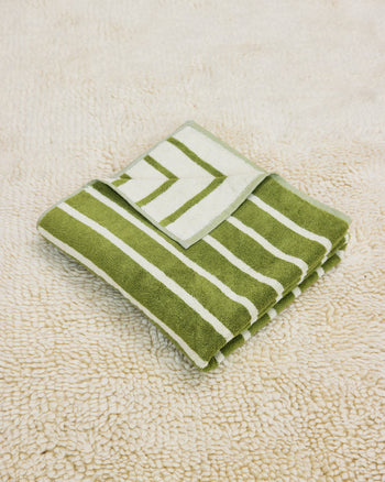 Green and white striped towel folded on a rug
