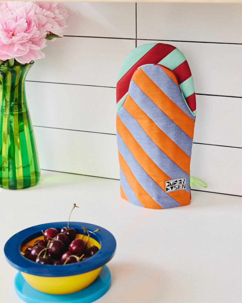 Pumpernickel oven mitt on kitchen counter with a bowl of cherries