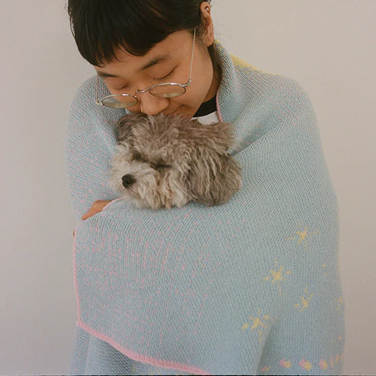 yaeji with small dog wrapped in pastel blue blanket