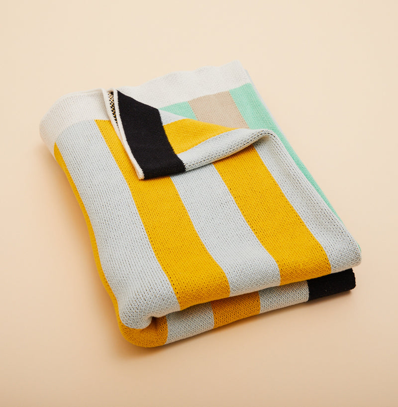 Dusen Dusen Stripe Throw. Cotton knit throw in multi-colored stripes with black and white border. 100% cotton, medium weight, soft & cozy. 50" W x 70" H. Machine wash cold and tumble dry low. Made in China