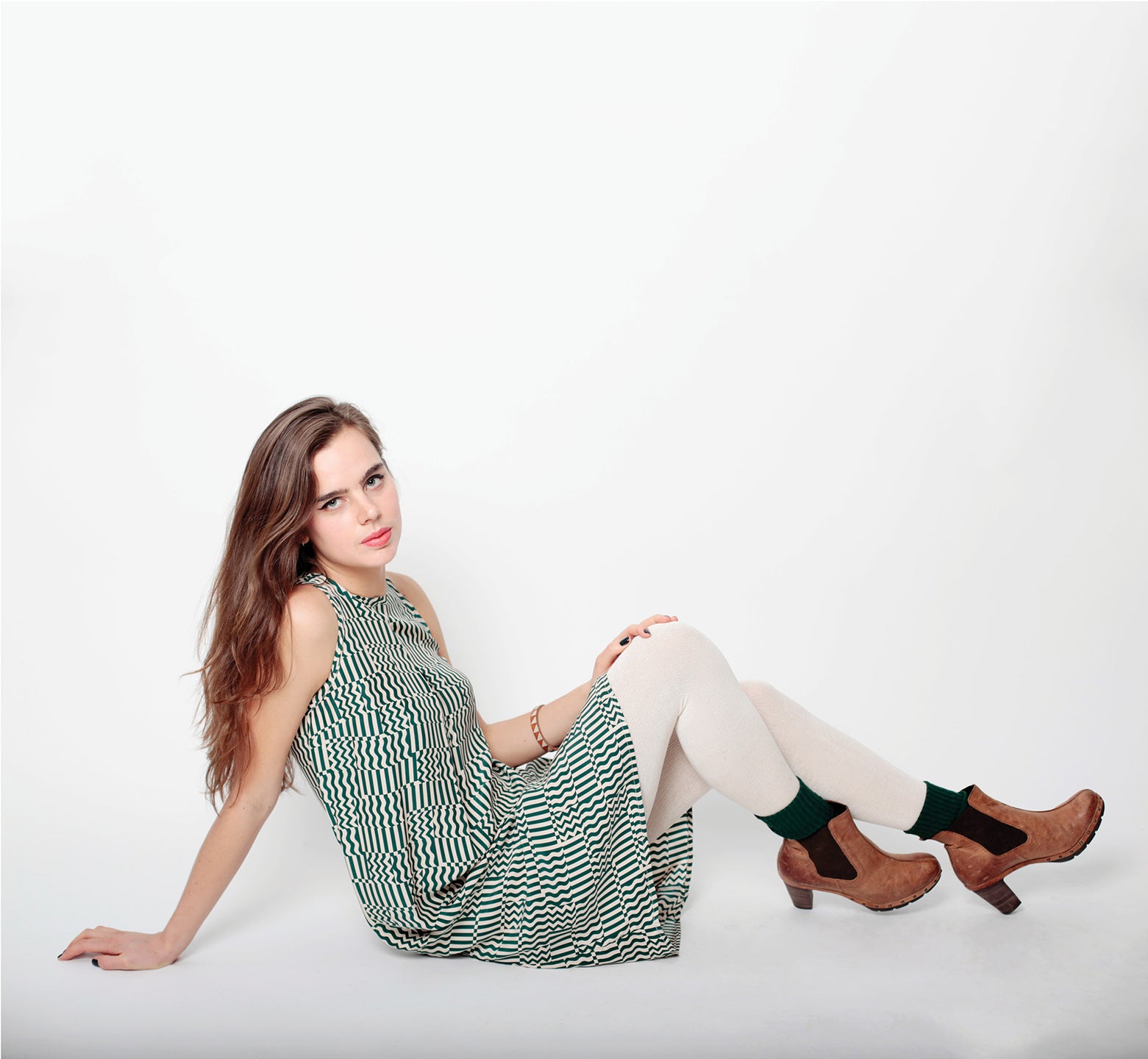 woman on floor in white tights and green squiggle grid dress sleeveless