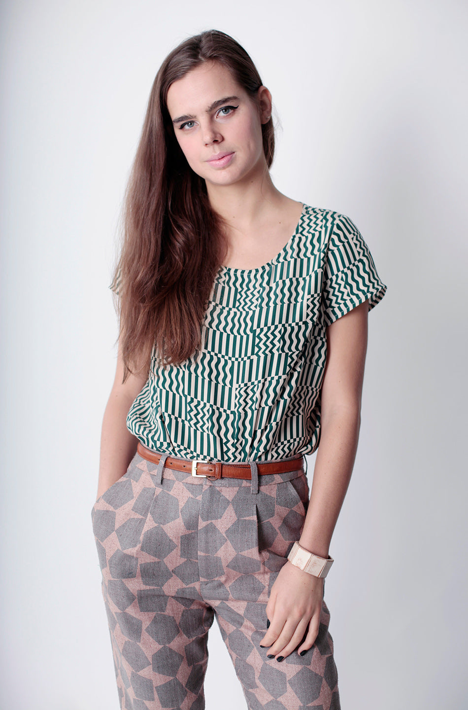 woman in squiggle gris top green and patterned pants with brown belt