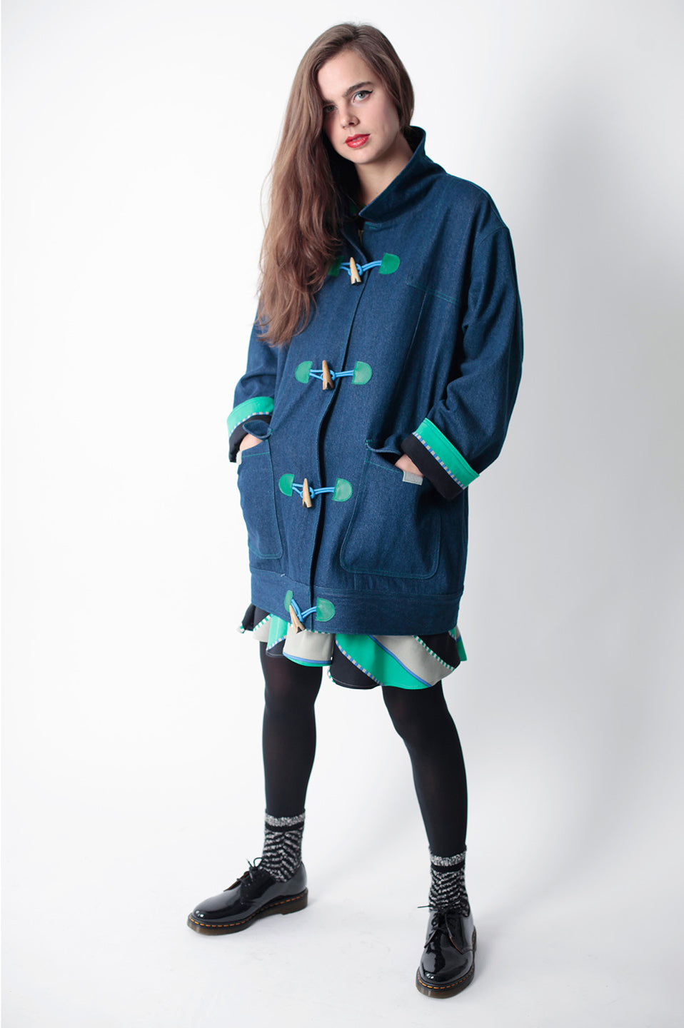 woman in denim raincoat with green pattern skirt poking out