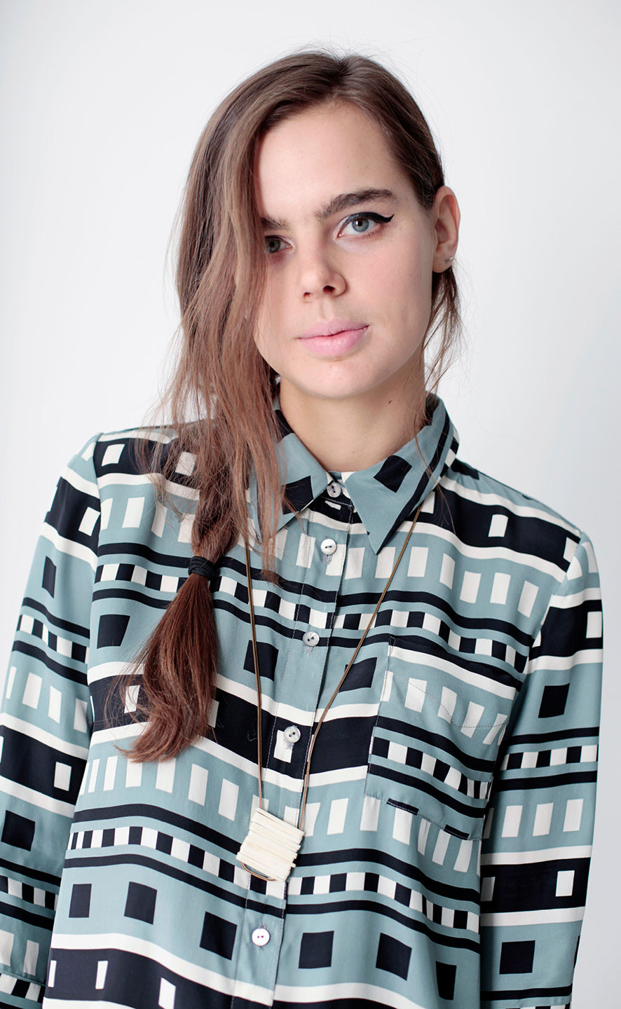 close up of woman in dusty blue, black and white button up with white long necklace
