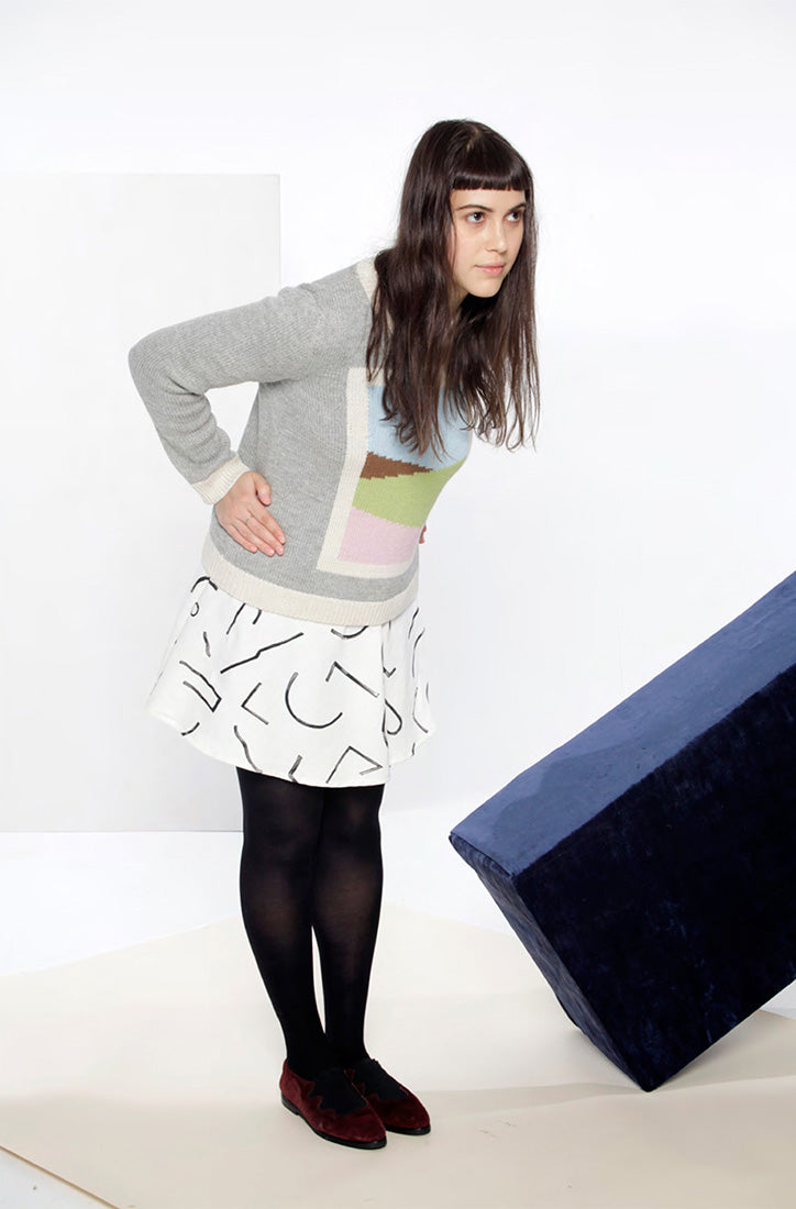 model in grey knit sweater with landscape motif and white skirt
