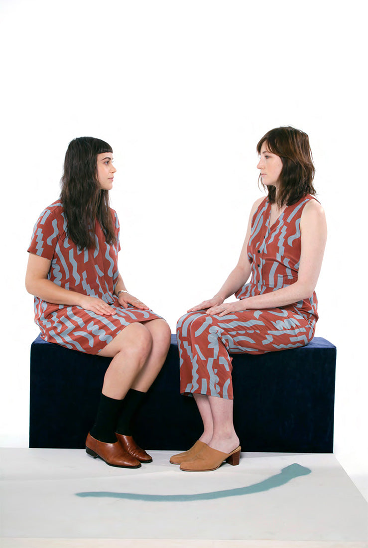 two models sitting in rust pattern clothing with blue squiggles