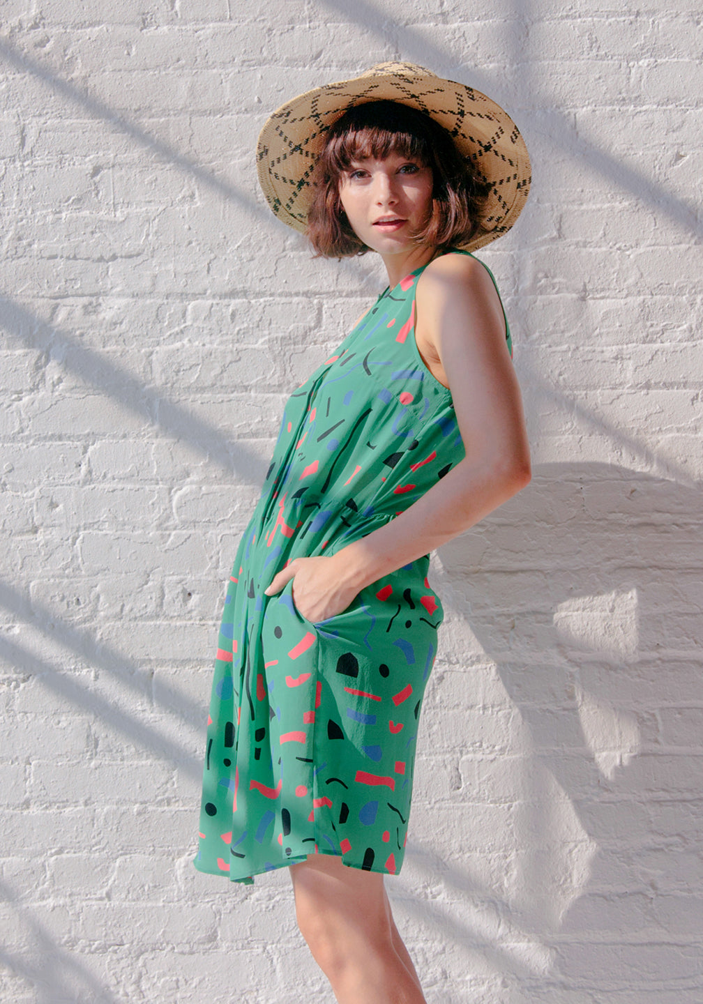 woman in straw hat with green romper with cut out pattern