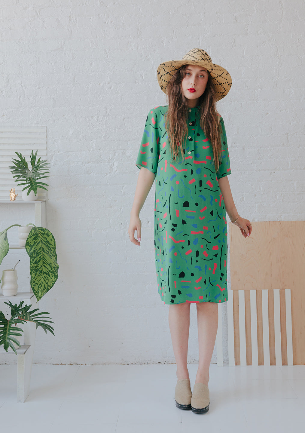 woman in straw hate with green button up collared dress with cut out pattern