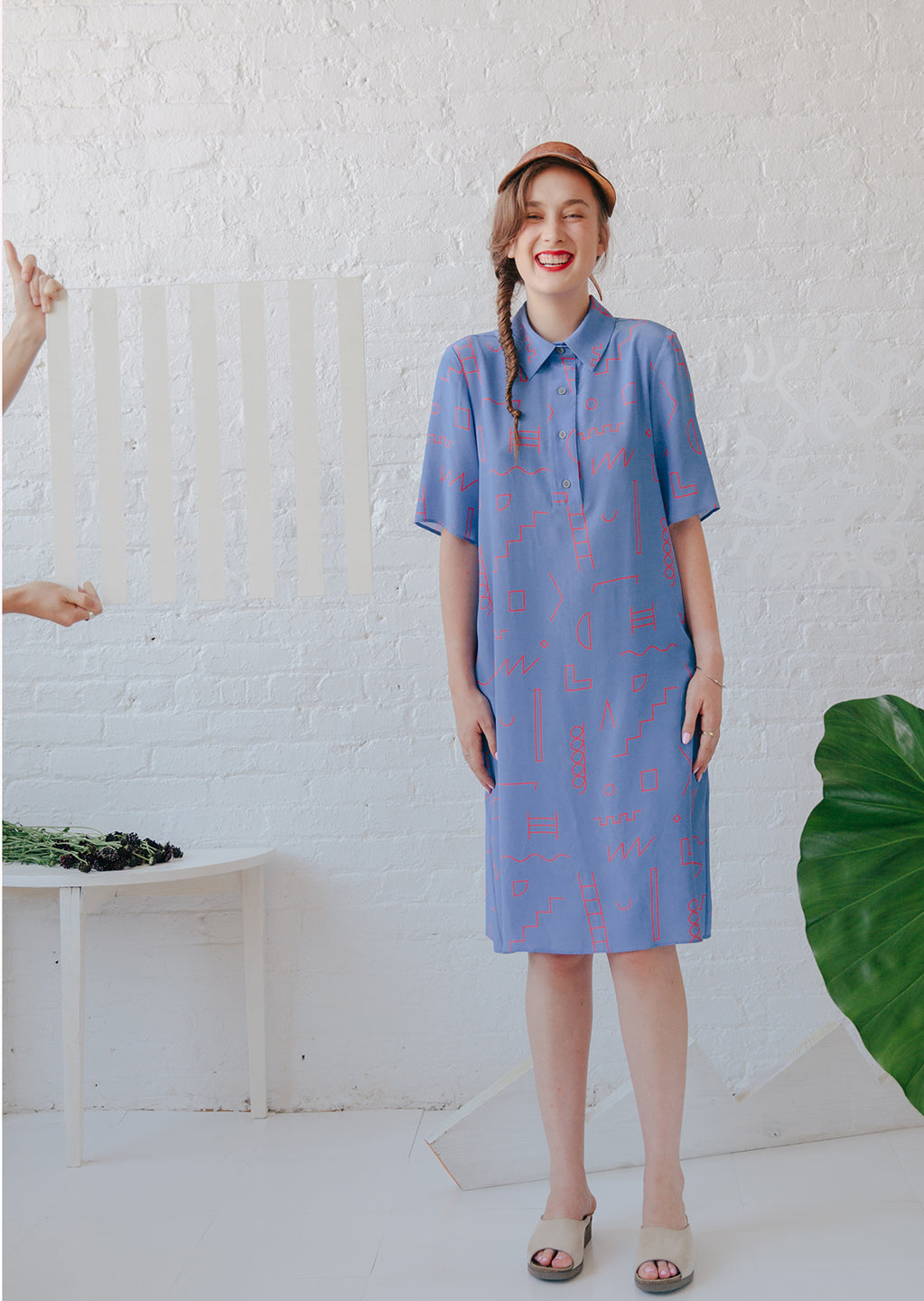 woman smiling with blue dress button up collared with red doodle pattern