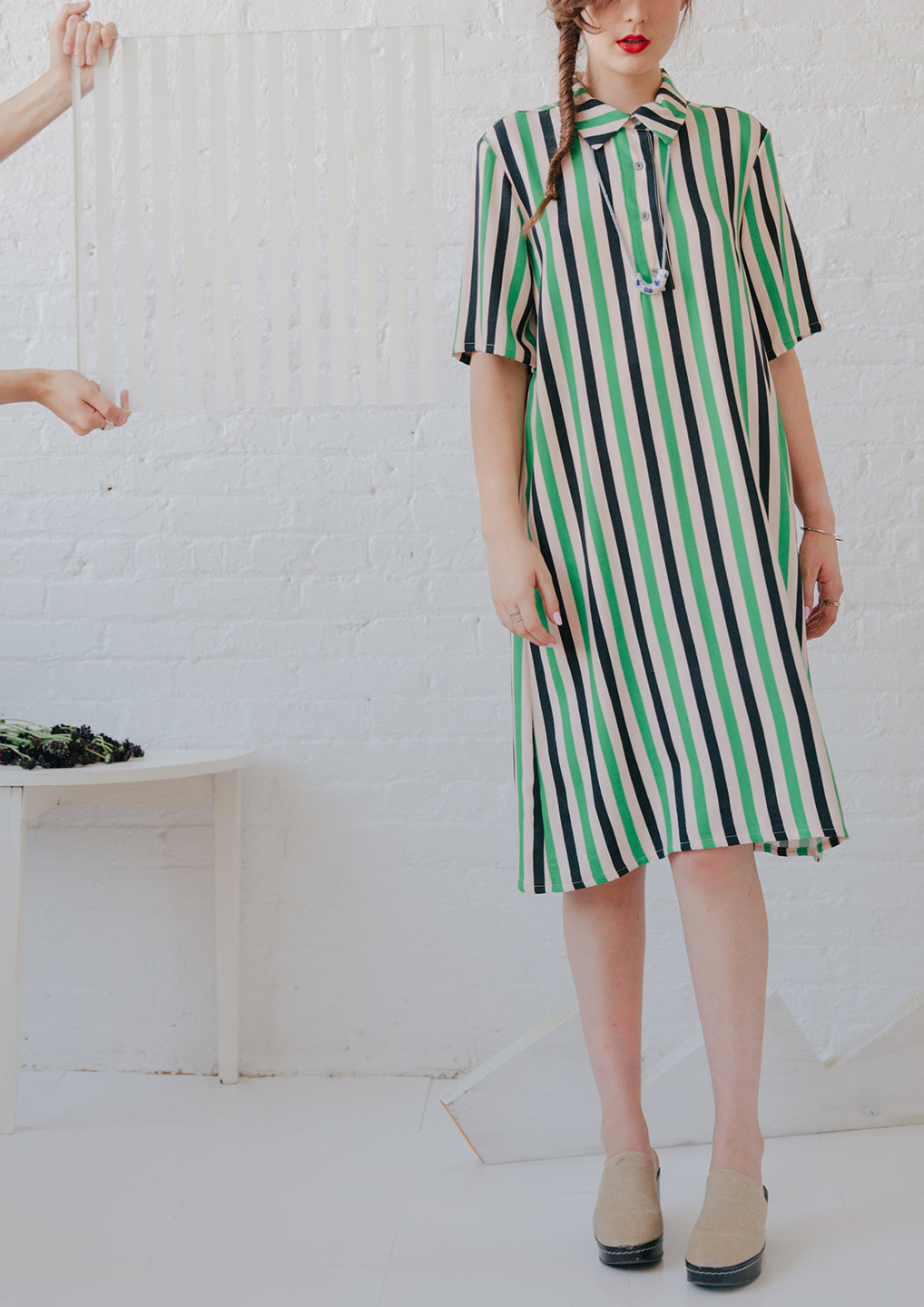 figure wearing collared dress in white black and green mid length dress