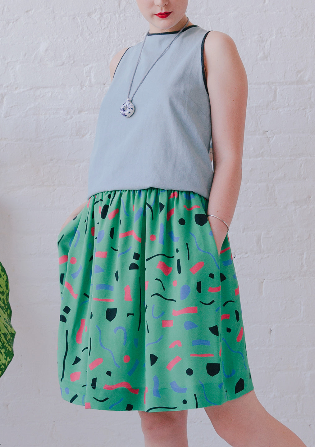 blue halter with long necklace and green cutout pattern skirt
