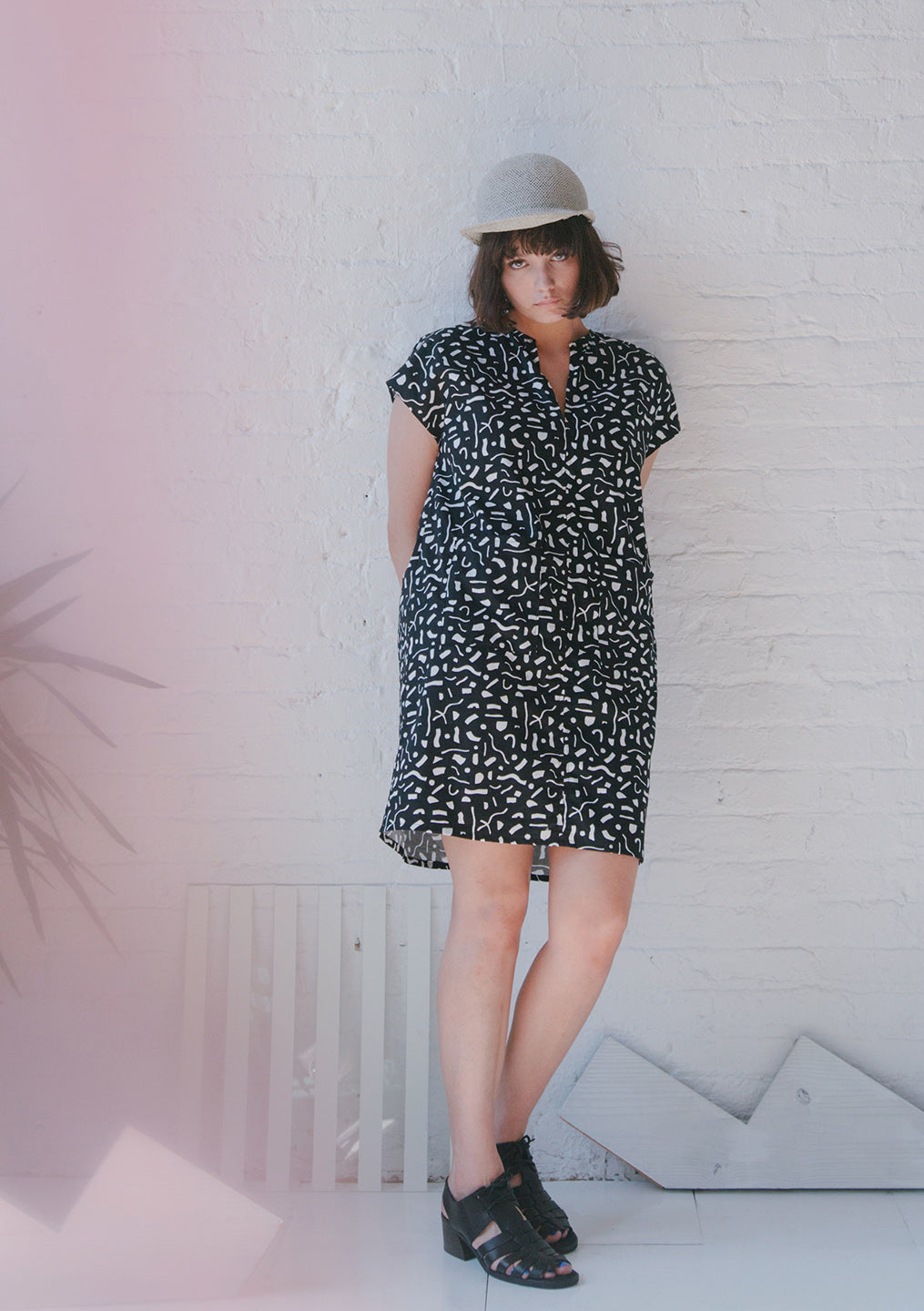 woman in white hat and black v neck dress with white cut out pattern small