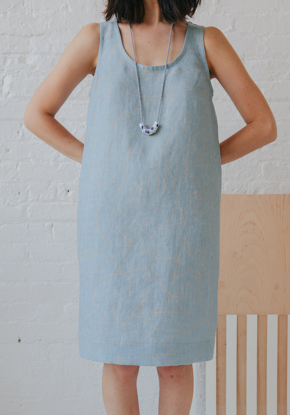 woman in denim blue dress, long necklace and white line pattern