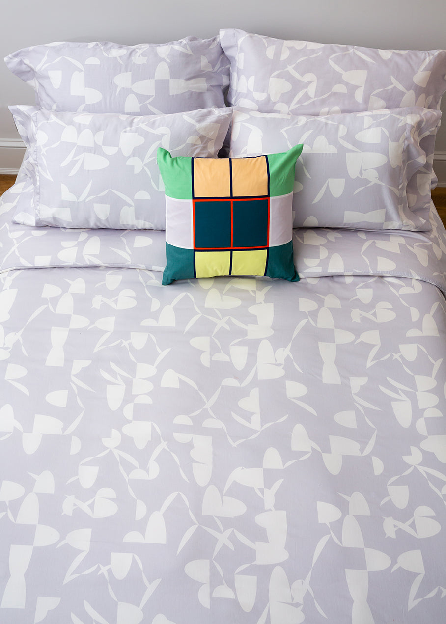 gray and white bedding with colorful pillow on top