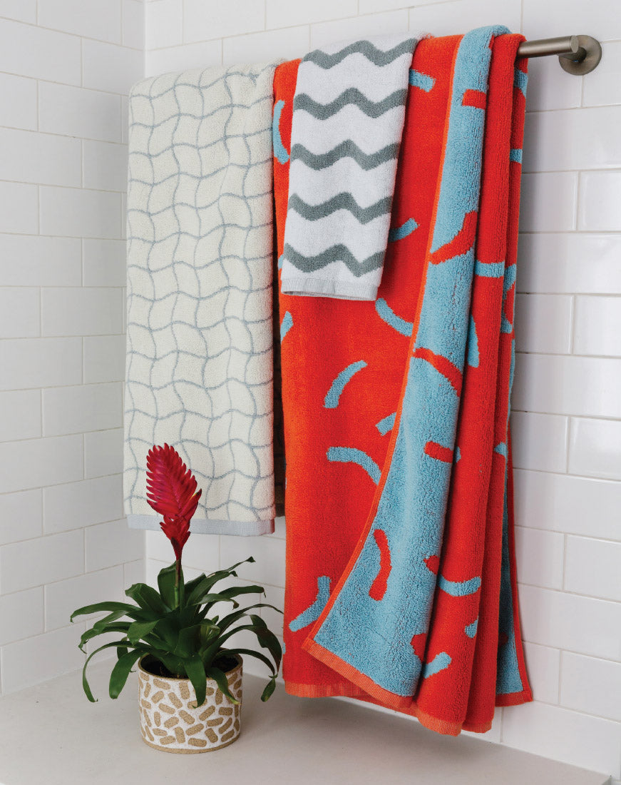 red towel and pastel towels with plant