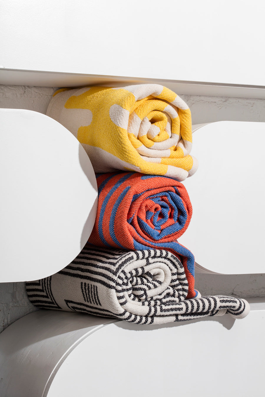 Three towels rolled up on shelf