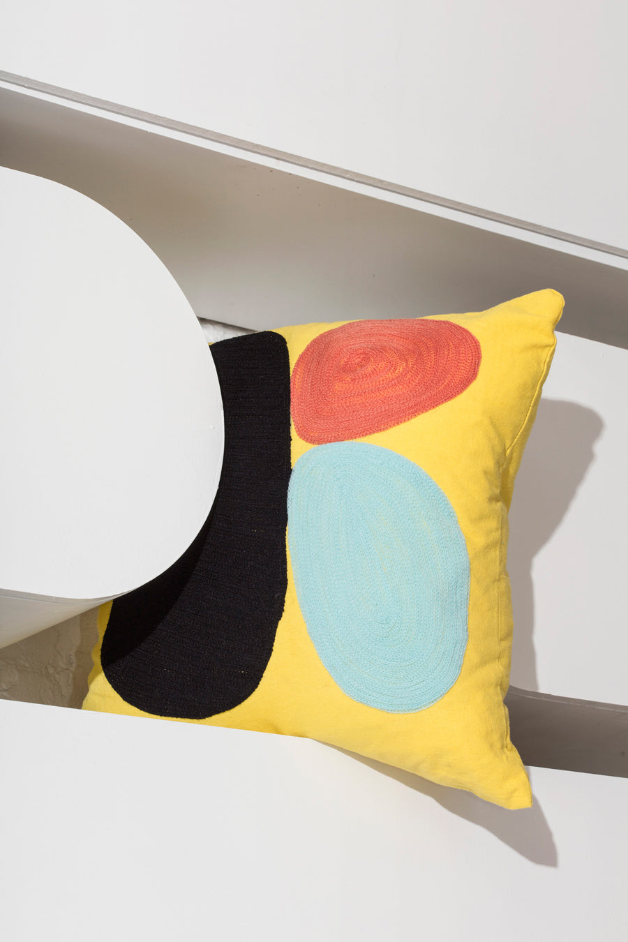 yellow pillow with red dot on shelf