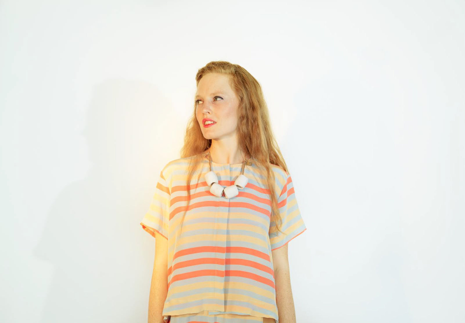 woman in orange red striped top with chunky necklace