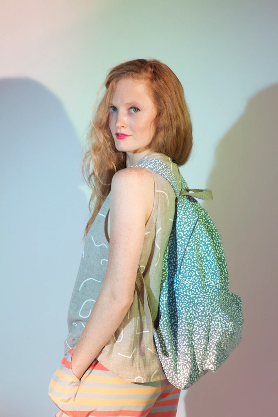 woman in grey tank with striped pants and blue backpack