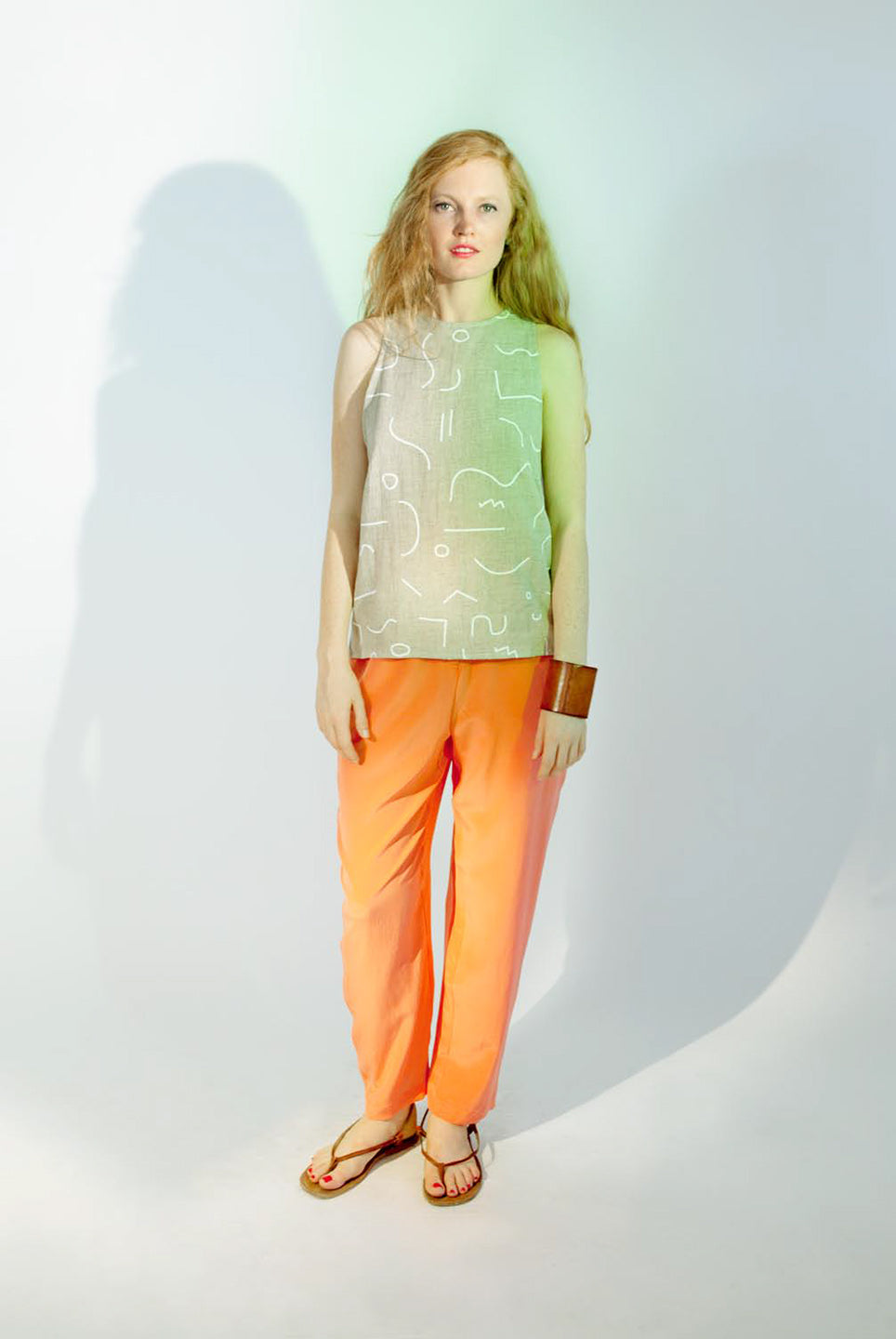 woman in grey line pattern top with big cuff and orange pants