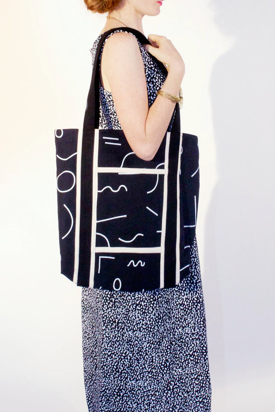 woman wearing back tote back with line pattern and strong black straps