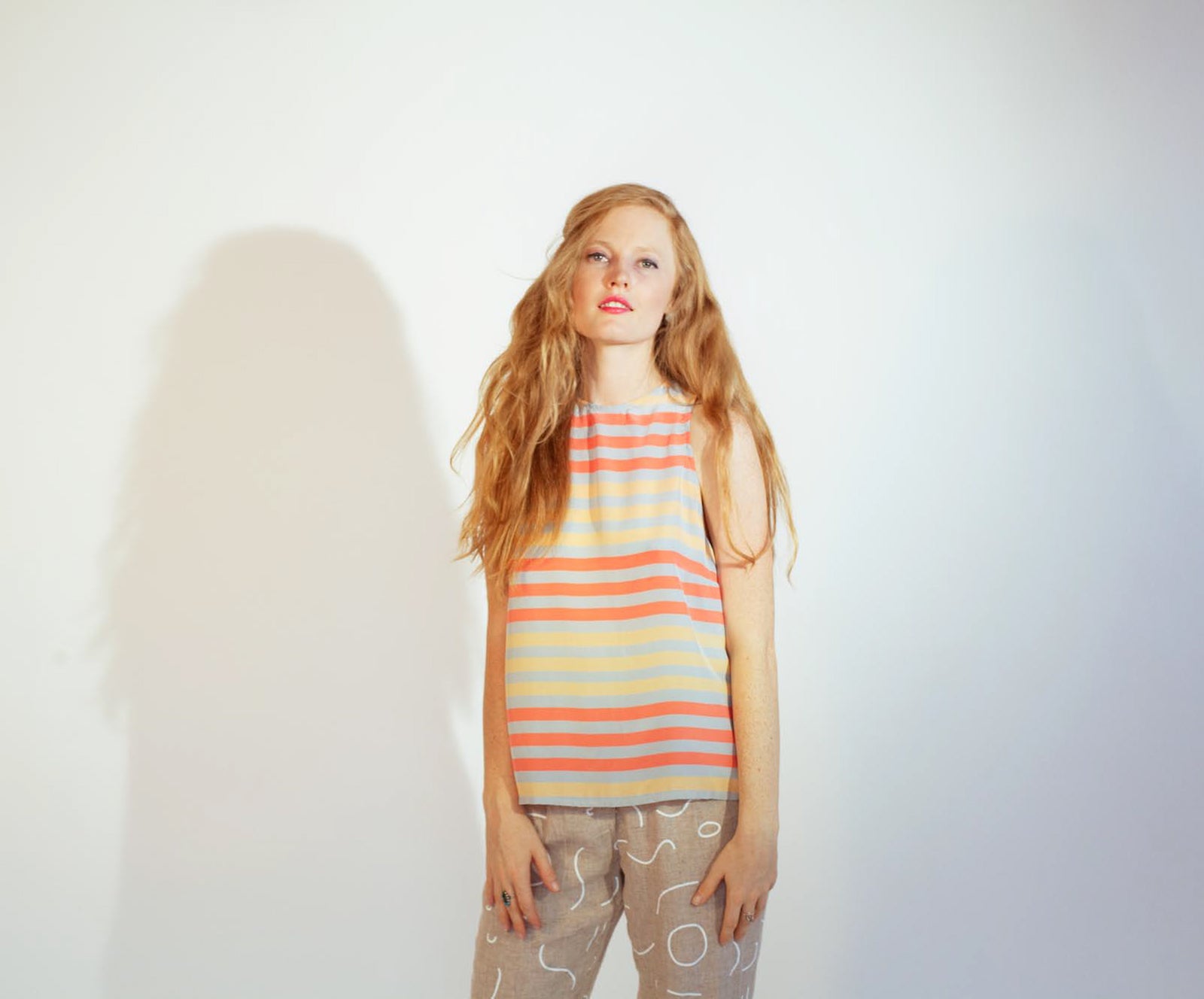 woman in orange and red tank with grey line pattern pants