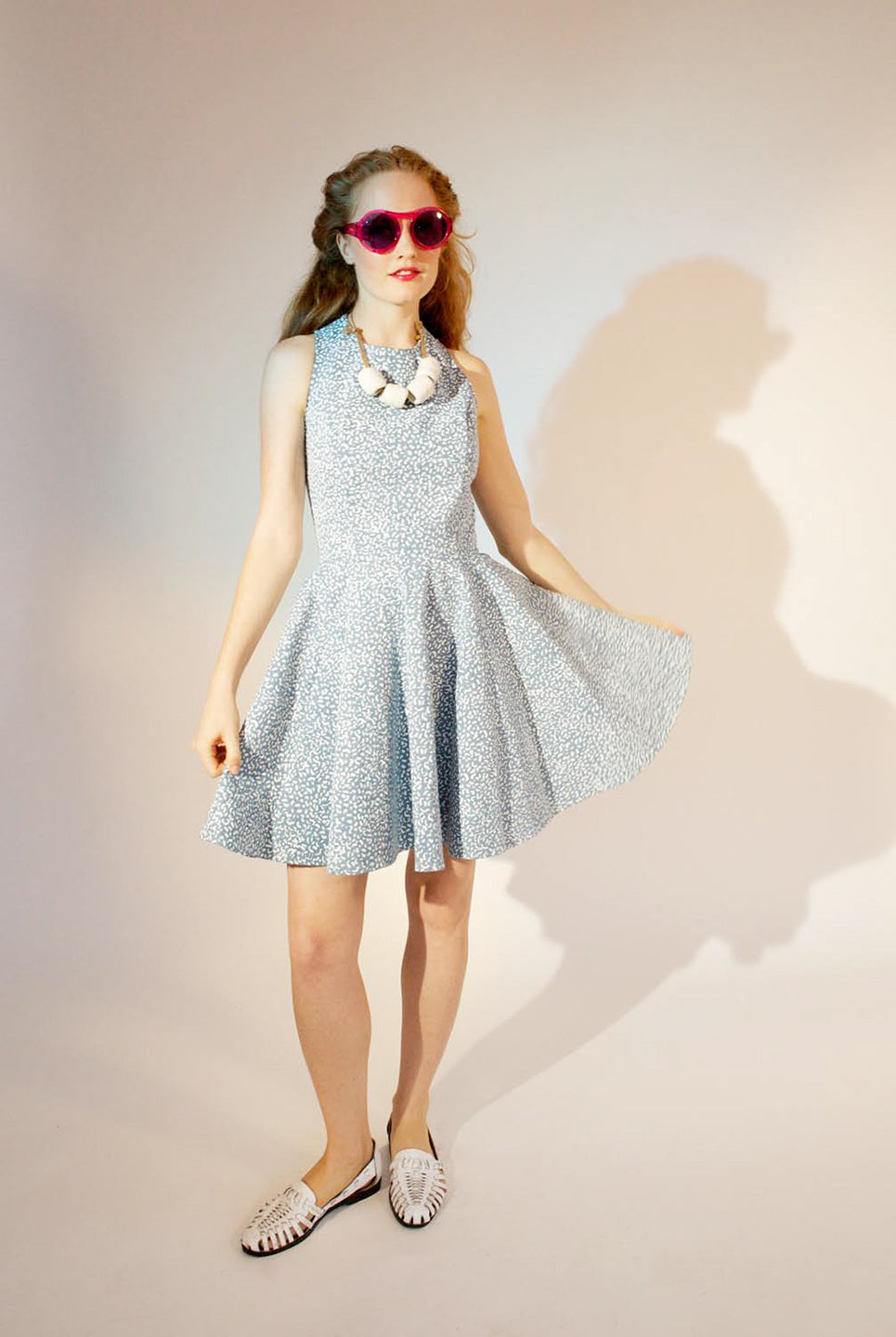 woman in ligth blue skater dress with chunky white necklace