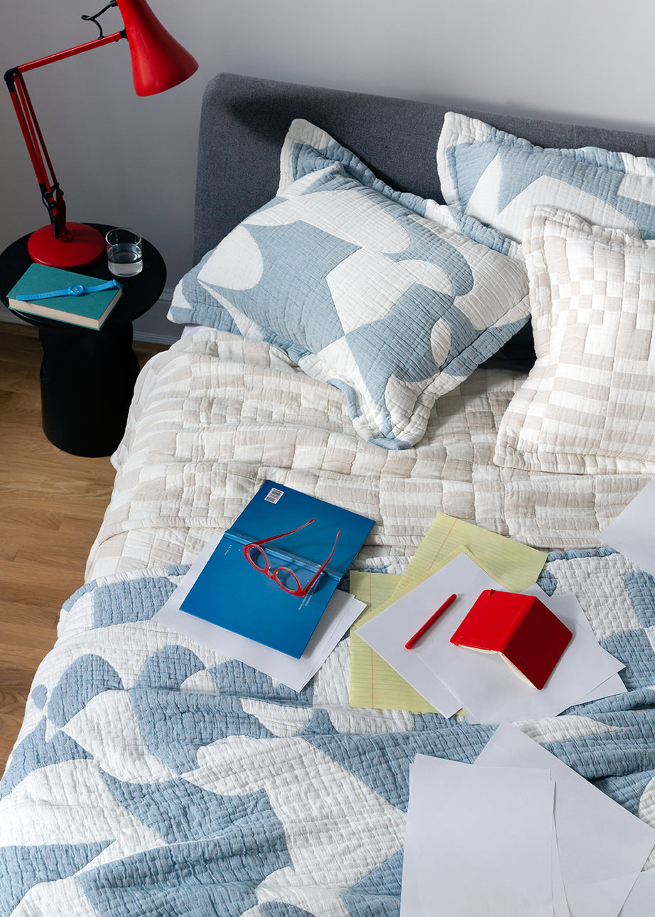 Hepta and Check coverlet with papers and glasses on bed