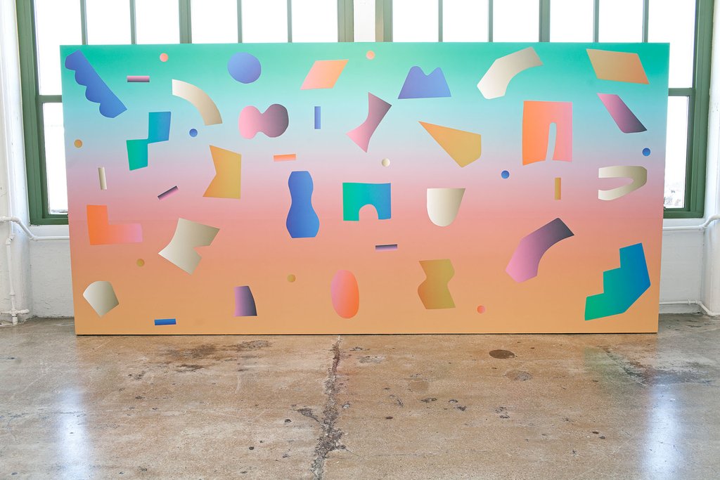 big wall of gradient from blue to orange with shapes on top on concrete floor