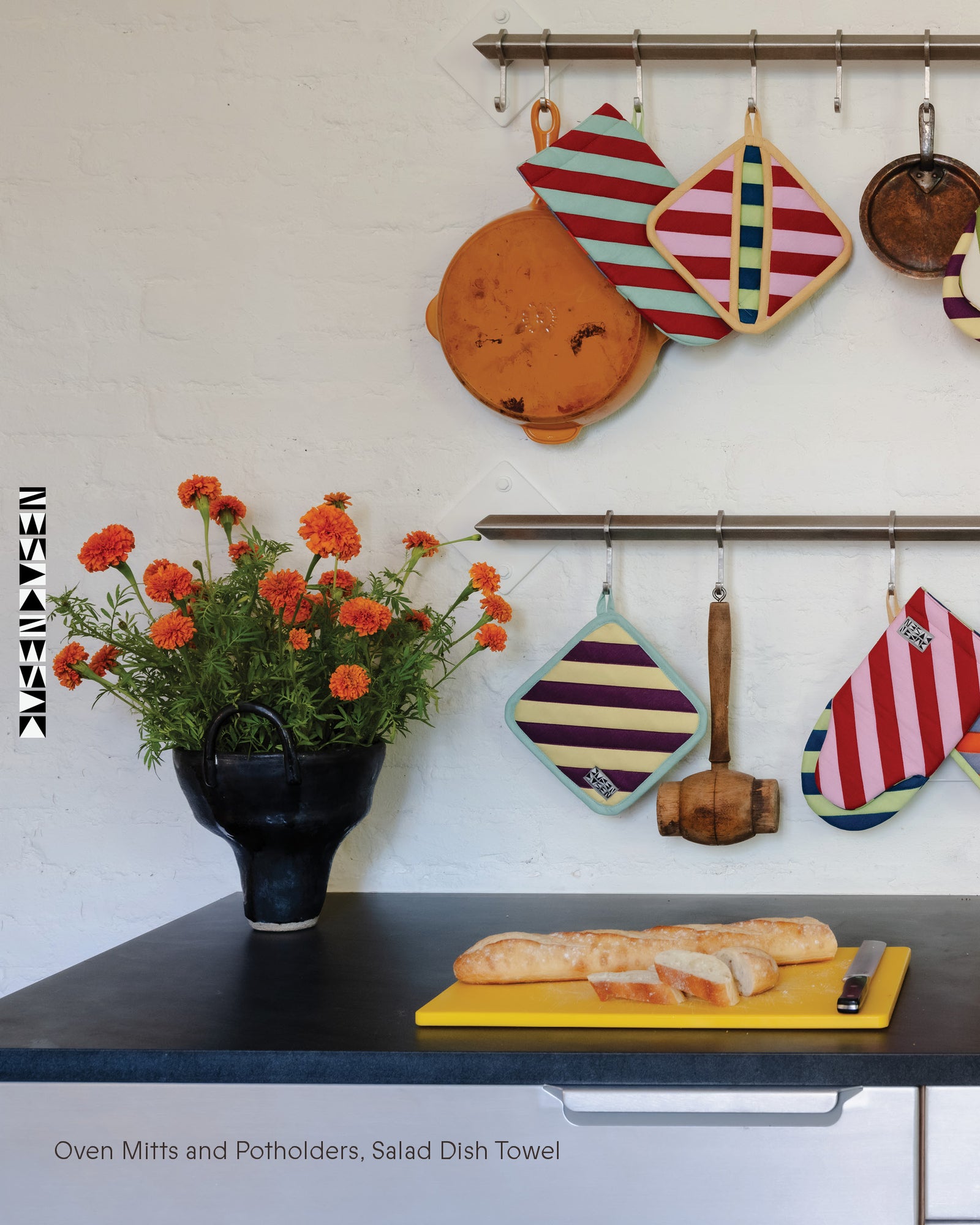 Kitchen scene with oven mitts, potholders, and a cutting board with bread.