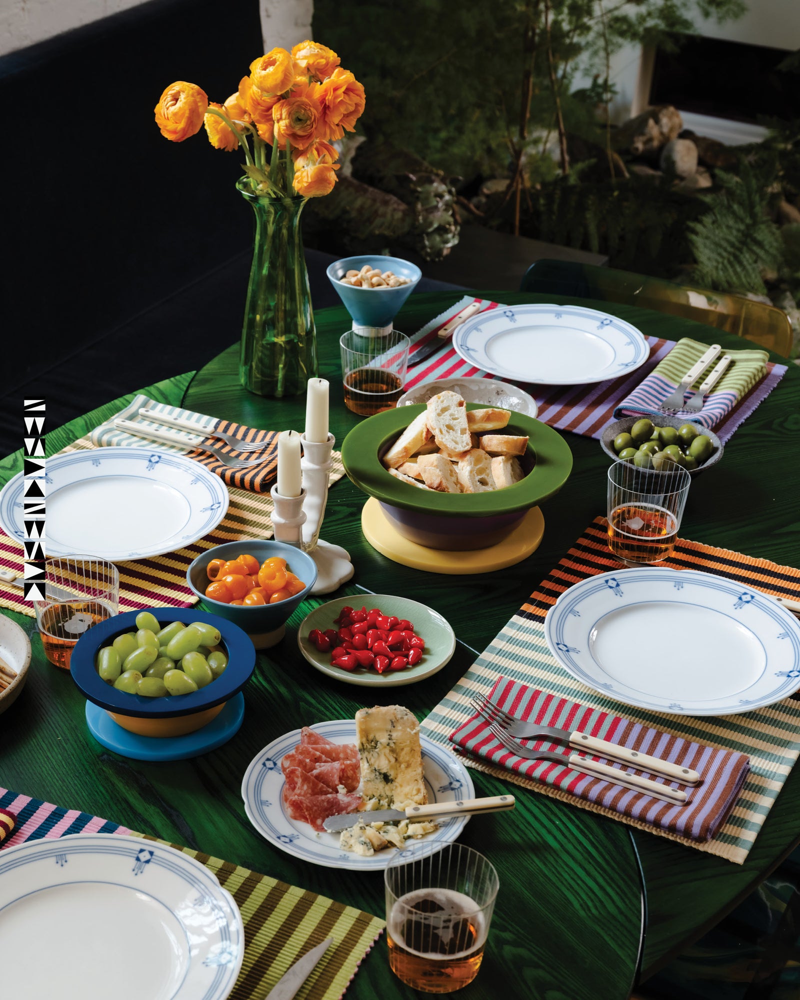 Dining table set with plates, glasses, and food on a striped tablecloth.