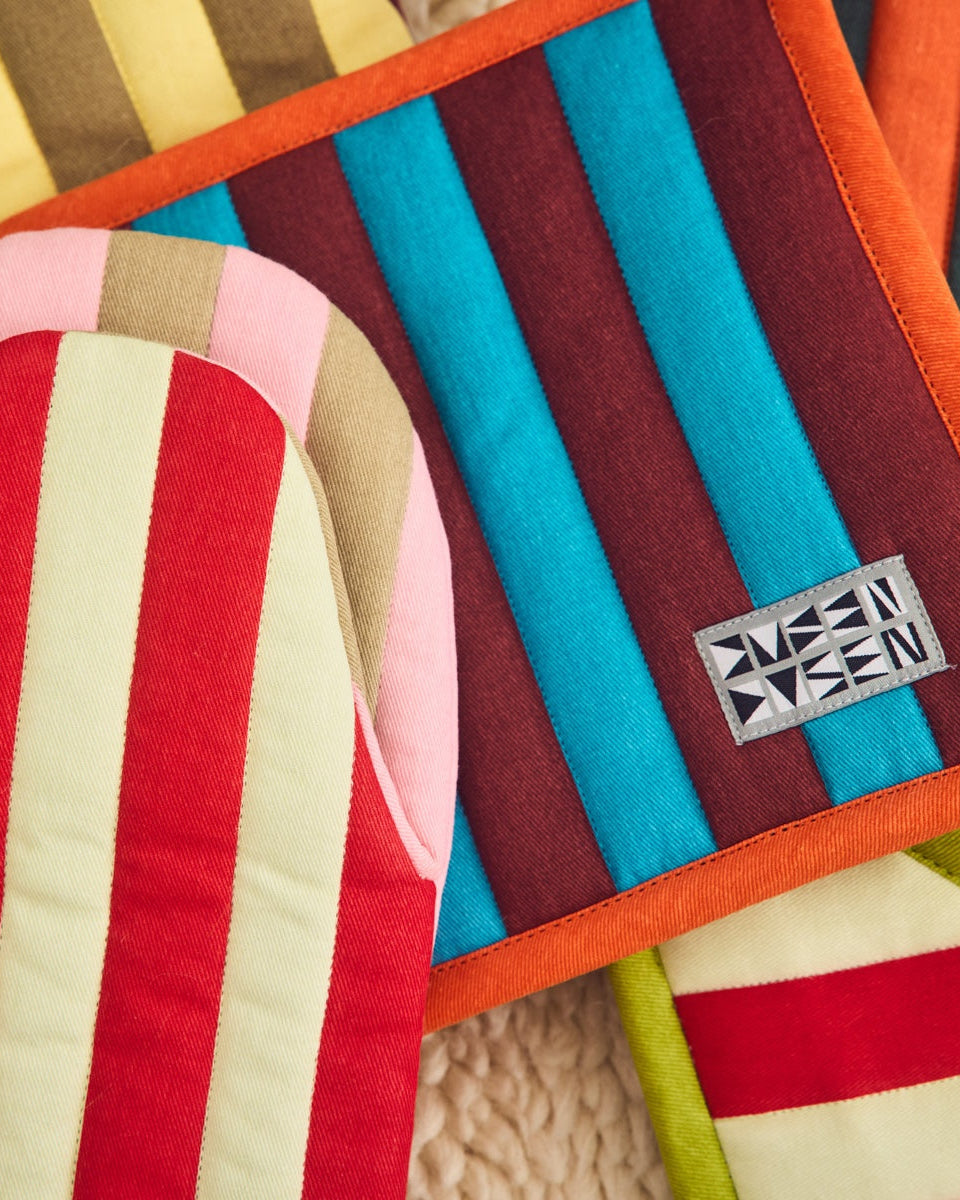 Colorful striped cushions with a brand logo on a textured surface