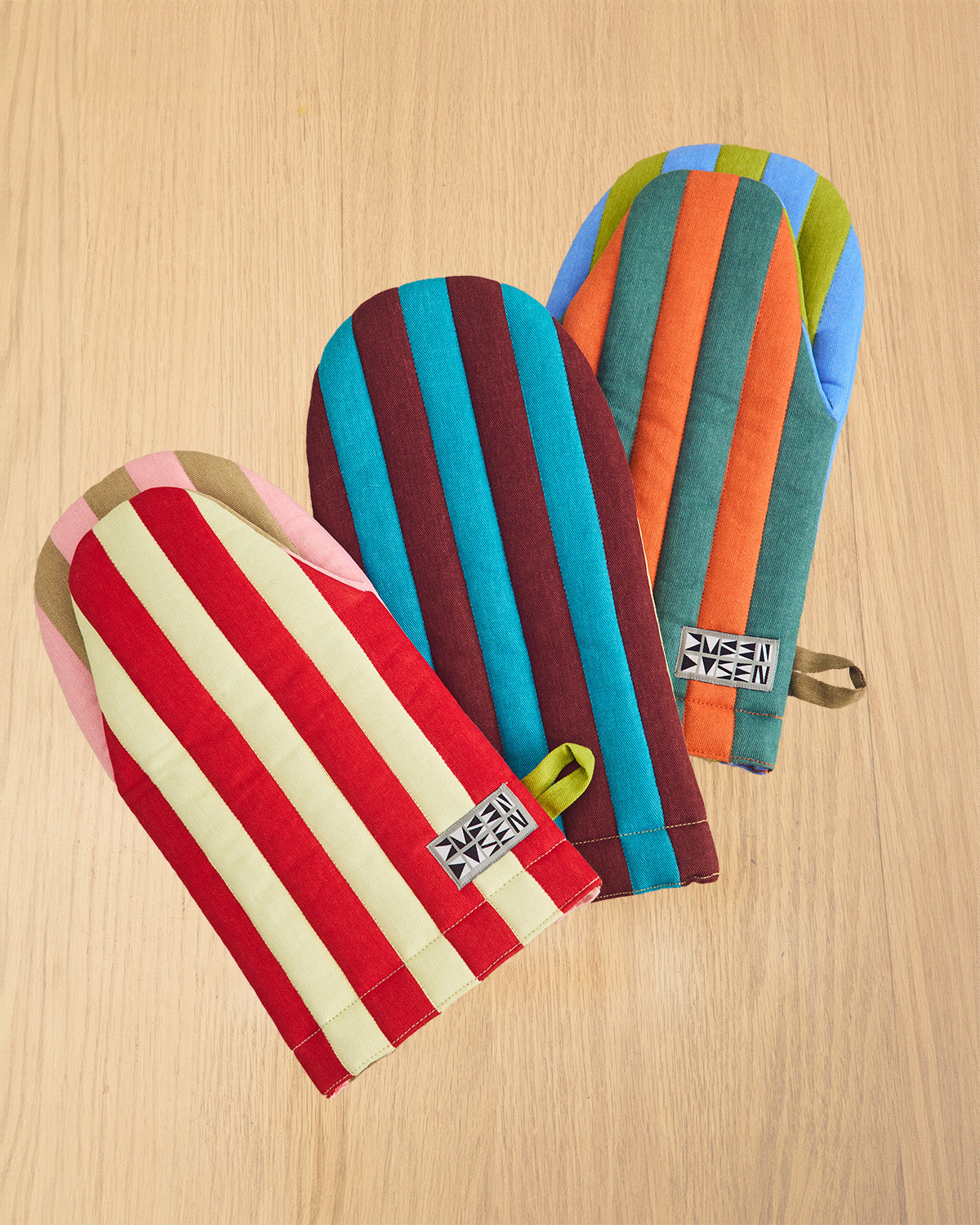 Colorful striped oven mitts on a wooden surface