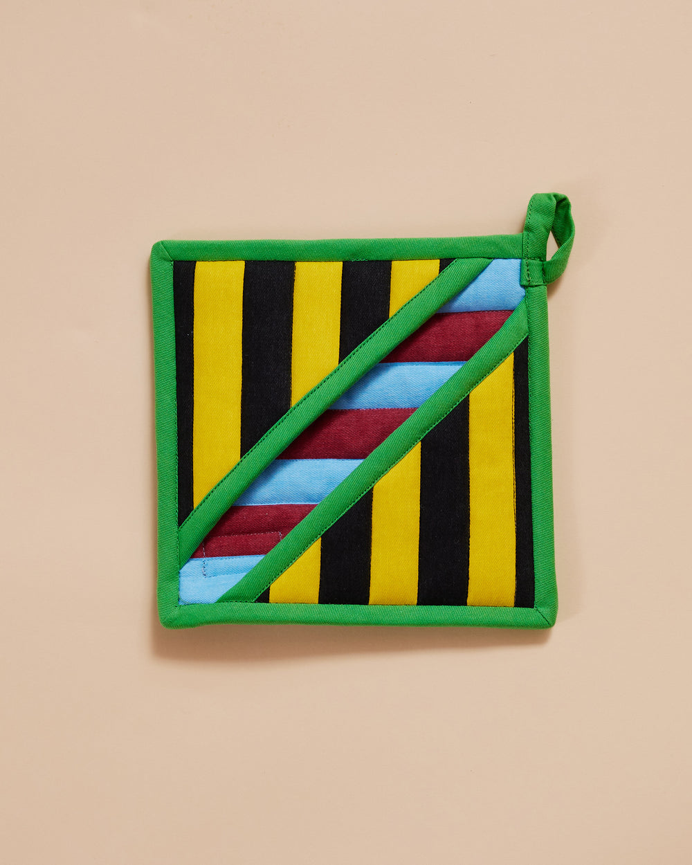 Dusen Dusen Stripe Pot Holder. Features a square pocket shape, top stitched brand label, and a side loop. 100% cotton quilted canvas base, with polyester fill. Stripe Pot Holder with contrast yellow, black, red and blue stripe pattern with an beige trim