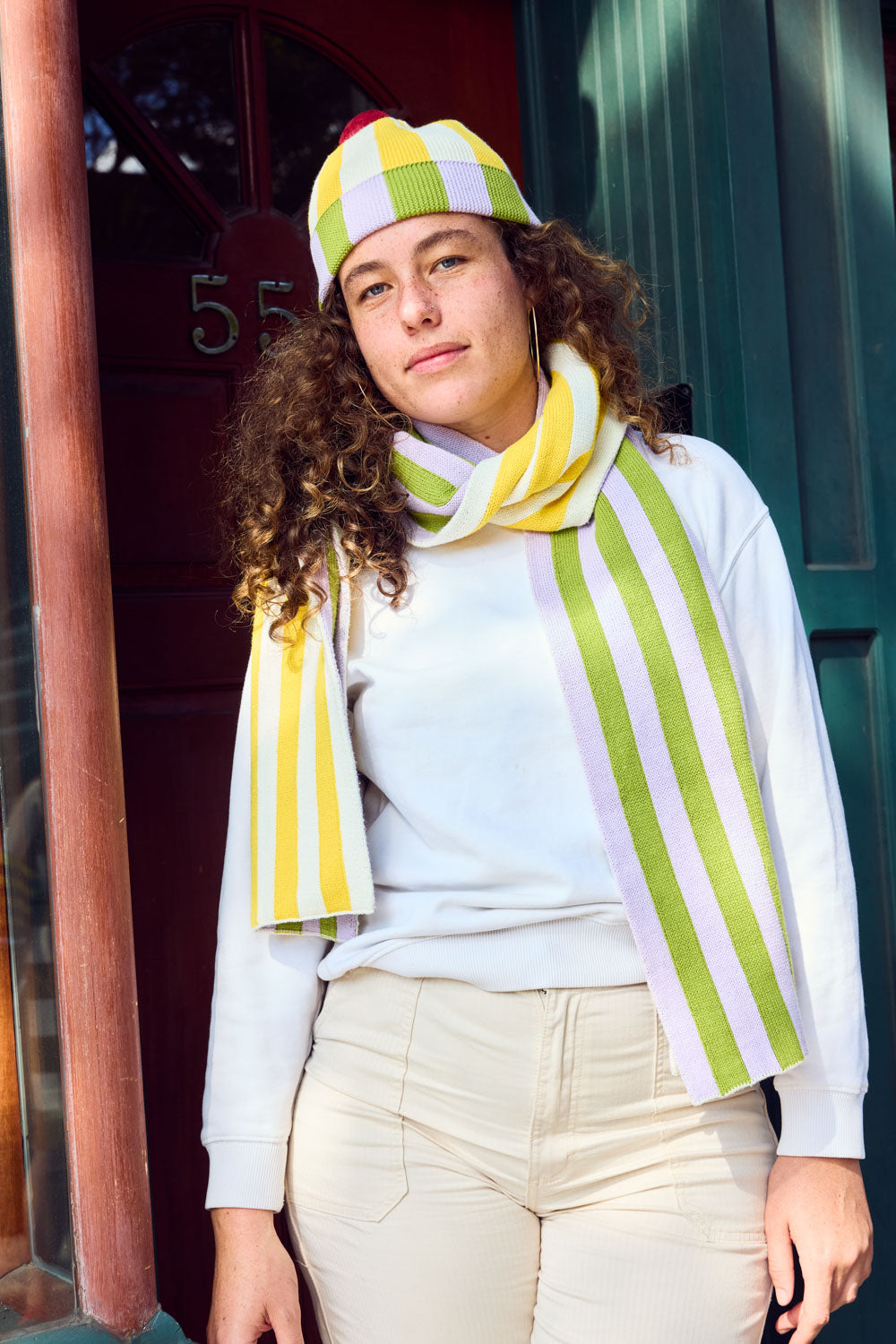 Squash Stripe Hat. Ribbed-knit pom beanie with contrasting yellow, white, lilac, and green stripes. 100% Cotton. Made in China.