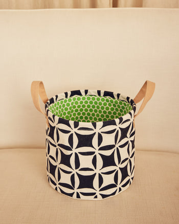 Fabric basket with geometric pattern and green interior on a beige surface