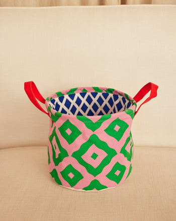 Colorful patterned storage basket with red handles on a beige surface