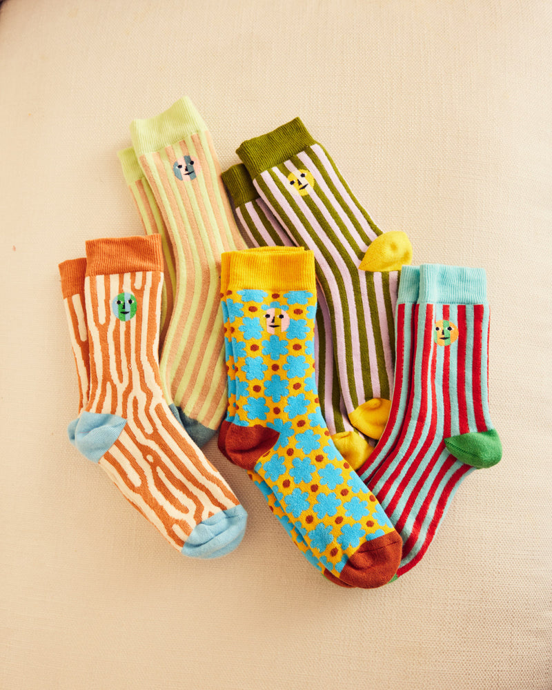 ["Five colorful socks, three striped and two patterns on a beige background"]