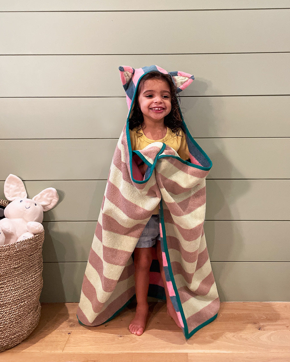 pink hooded towel on little girl in front of shiplap wall 