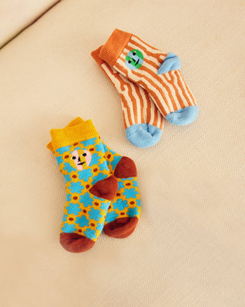 Two pairs of colorful children's socks on a beige surface