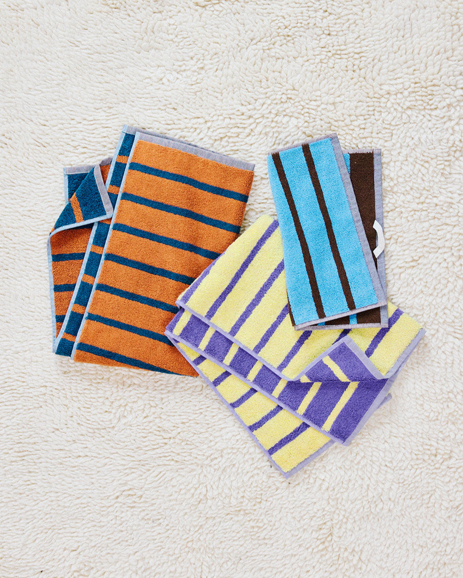 Heron Washcloth, Warbler and Goldfinch Hand towels on a rug 