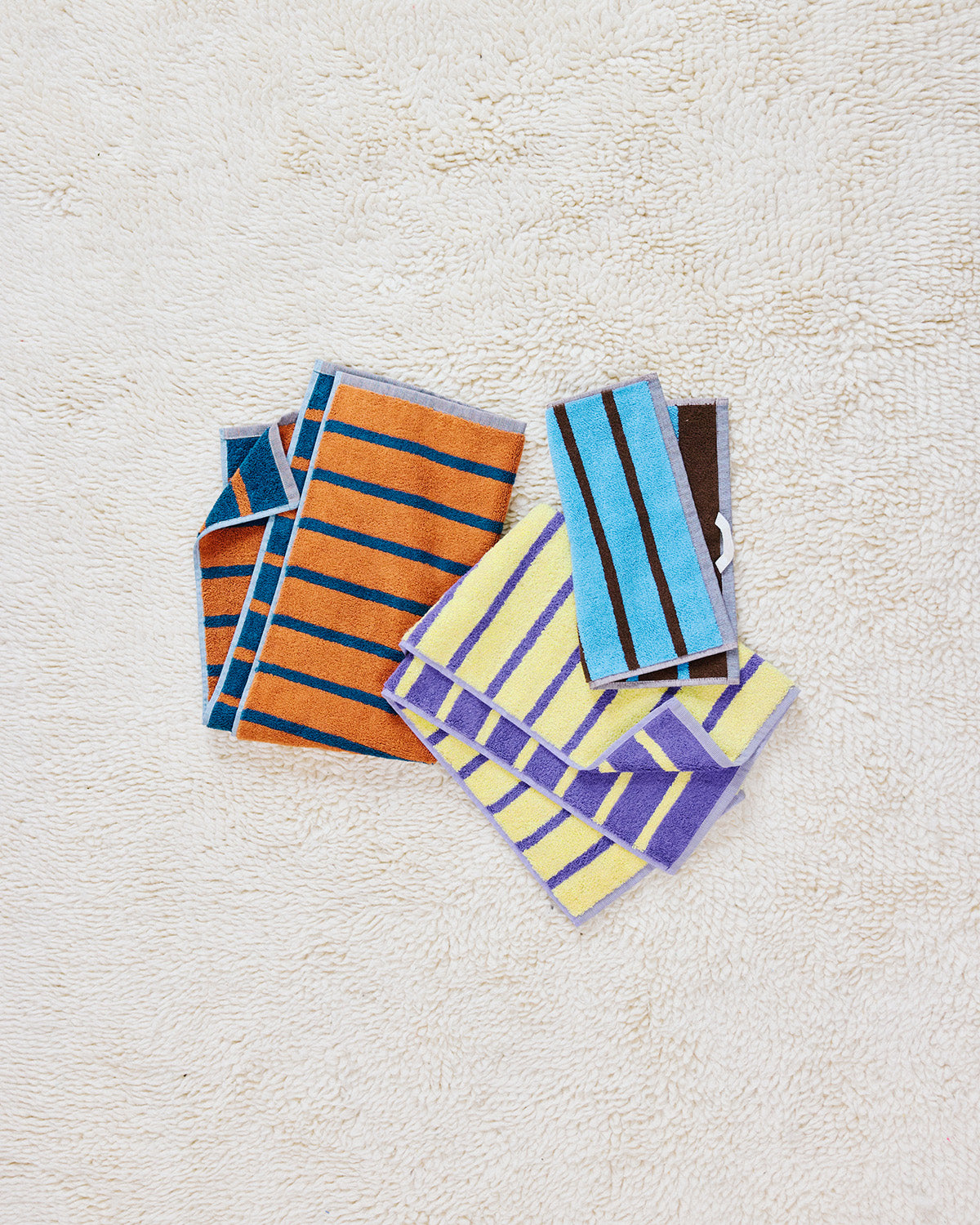 Heron Washcloth, Warbler and Goldfinch Hand towels on a rug 