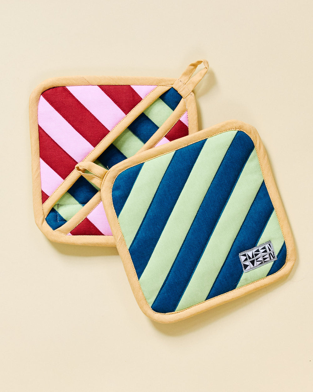 Two Brioche striped pot holders on a beige background 
