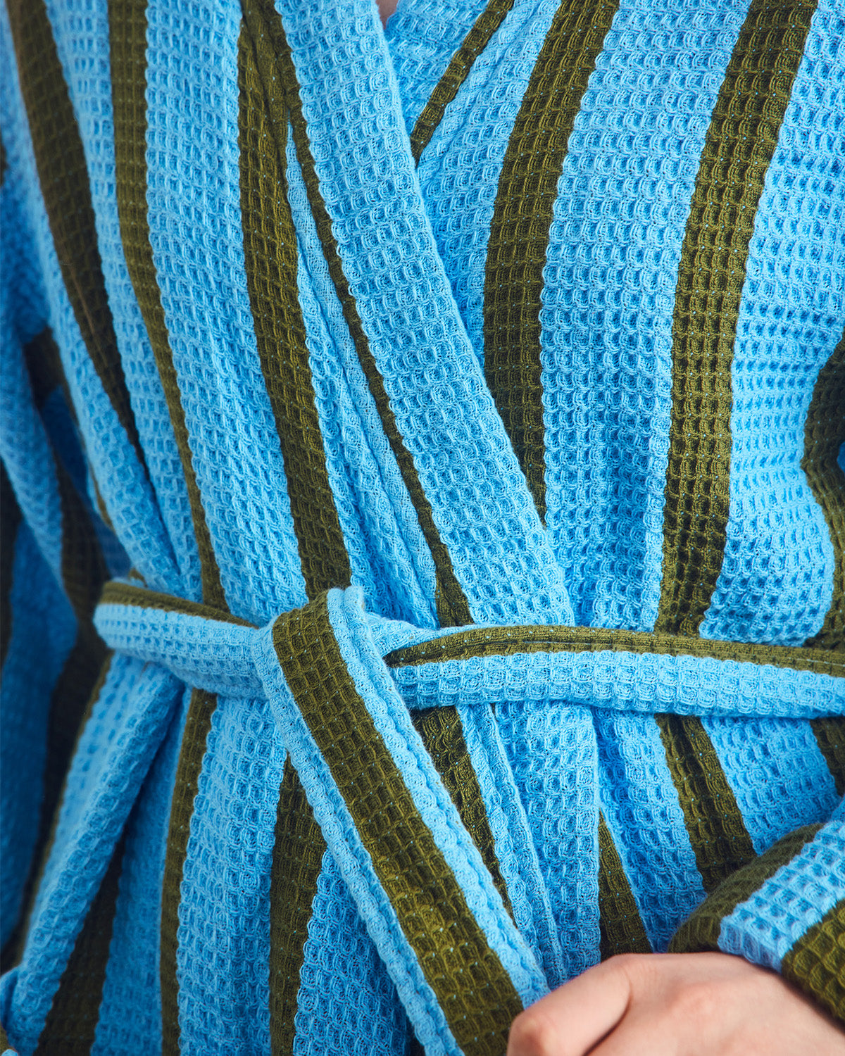 Close-up of a blue and green striped waffle robe with a textured pattern.