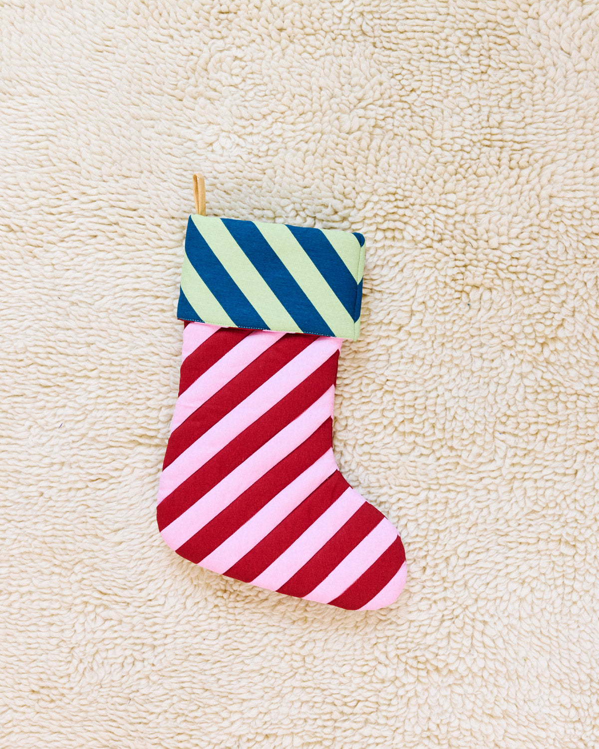 red and pink striped christmas stocking on beige rug