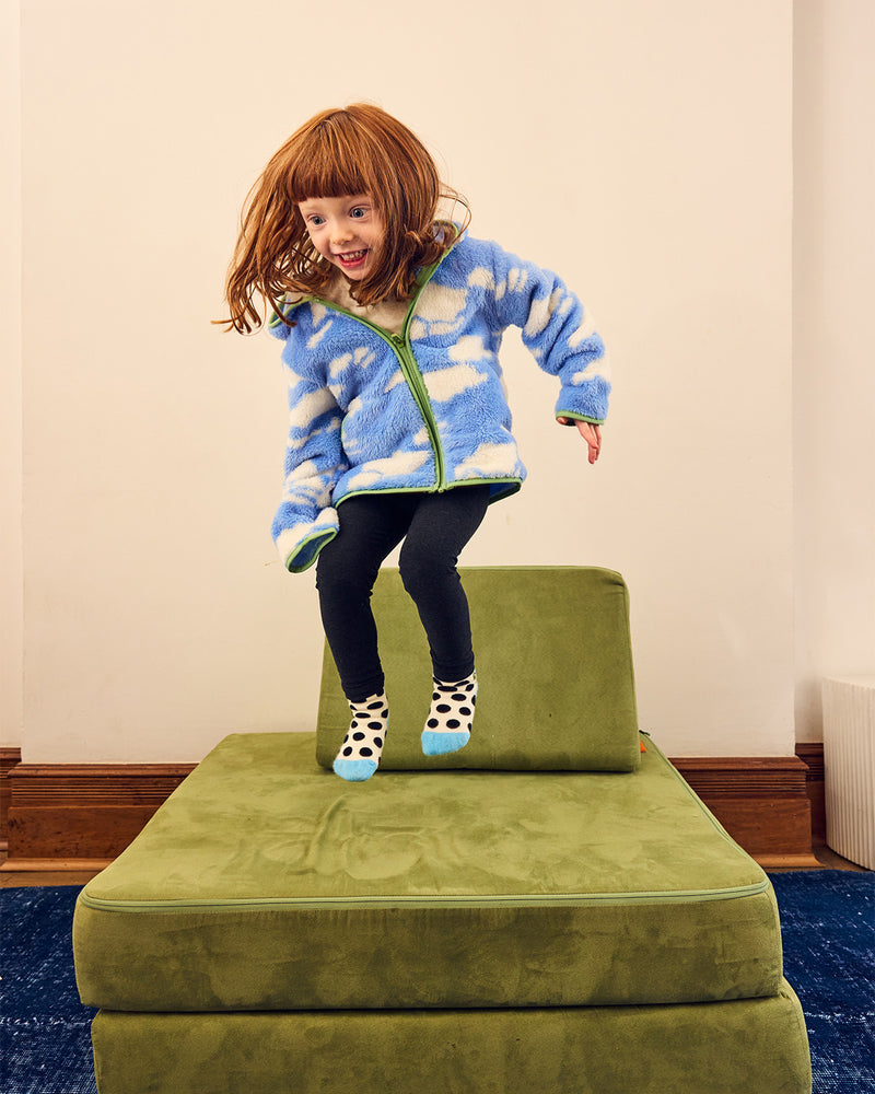 cloud pattern hooded on girl jumping on green chair with blue rug